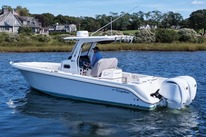 Slide: The Image of 2023 Edgewater 262CC boat cruising on a scenic waterway near coastal homes. - 6