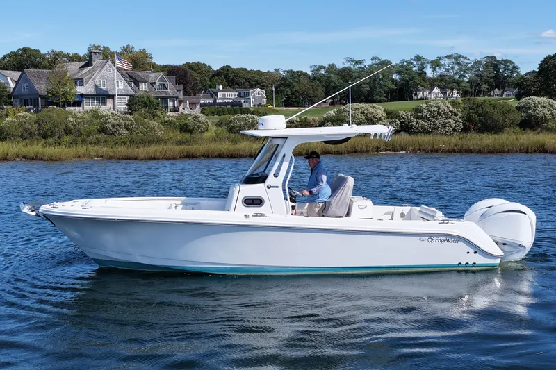 Slide: The Image of 2023 Edgewater 262CC boat cruising on a scenic lake near waterfront homes. - 7
