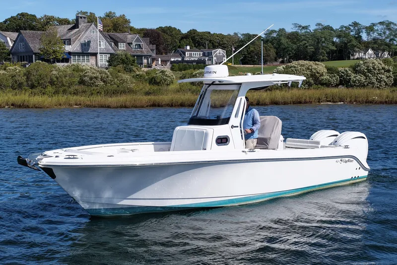 Slide: The Image of 2023 Edgewater 262CC boat cruising on a scenic lake near luxury homes. - 8