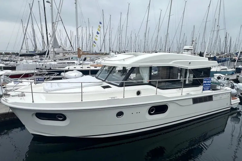 The Image of 2024 Beneteau Swift Trawler 41 Sedan docked in a marina, surrounded by sailboats. - 1