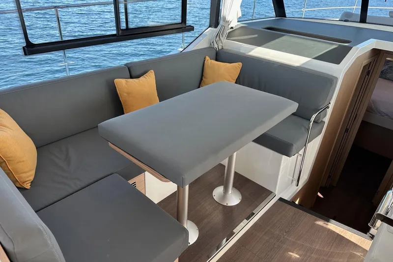 Slide: The Image of 2024 Beneteau Swift Trawler 41 Sedan interior with gray seating and table, ocean view. - 46