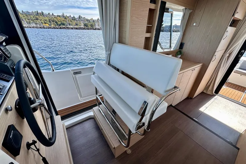 Slide: The Image of 2024 Beneteau Swift Trawler 41 Sedan interior with helm, seating, and scenic water view. - 49