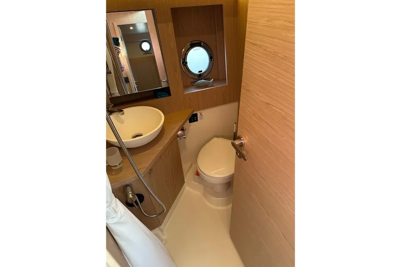 Slide: The Image of 2024 Beneteau Swift Trawler 41 Sedan bathroom with modern fixtures and porthole window. - 64