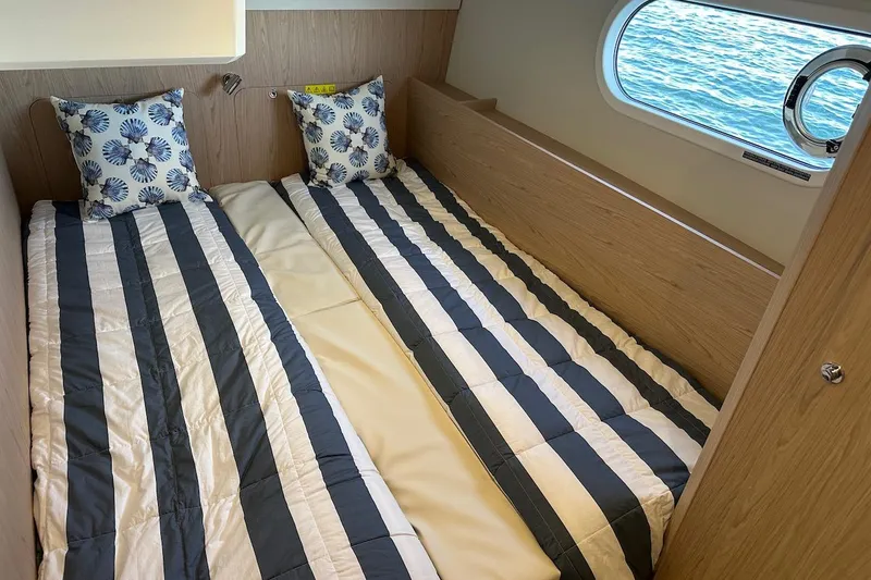 Slide: The Image of 2024 Beneteau Swift Trawler 41 Sedan cabin with twin beds and nautical-themed decor. - 68
