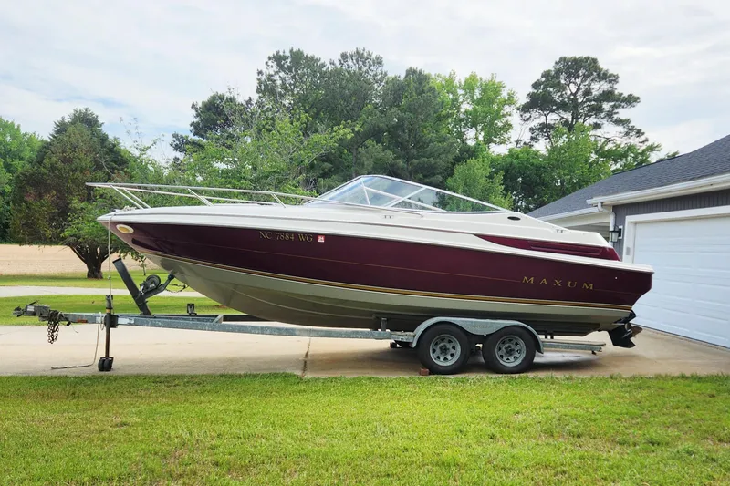 The Image of 1995 Maxum 2300 SC boat on trailer, parked in driveway, surrounded by trees. - 0