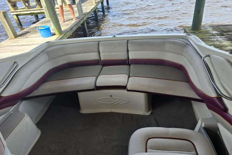 Slide: The Image of 1995 Maxum 2300 SC boat interior with cushioned seating near a wooden dock. - 11