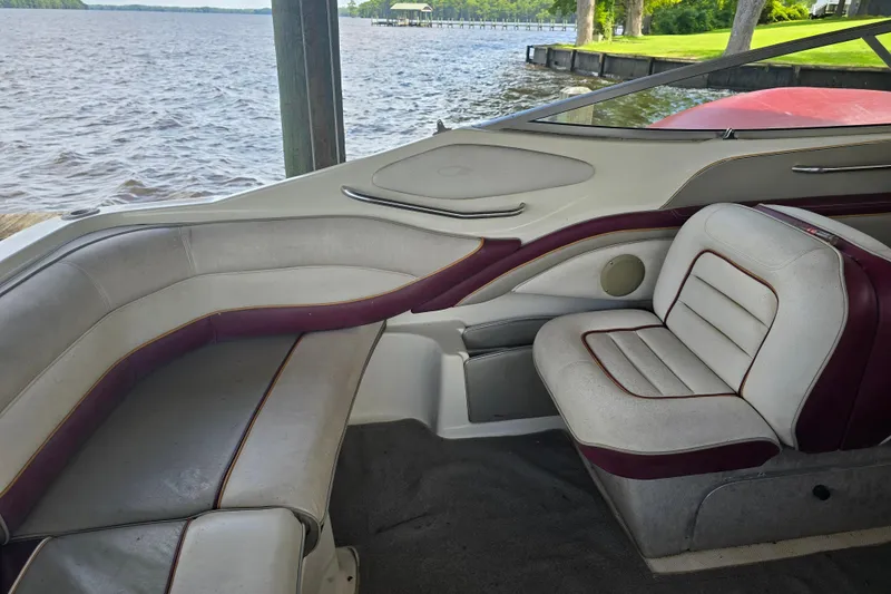 Slide: The Image of Interior of a 1995 Maxum 2300 SC boat with cushioned seating by the water. - 14