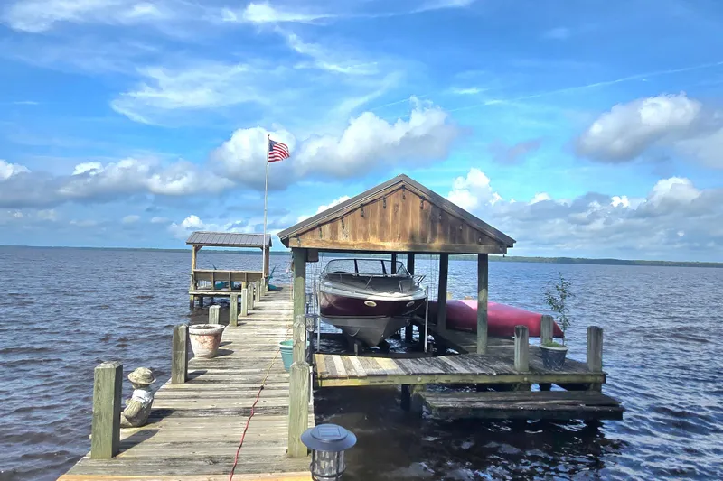 Slide: The Image of Docked 1995 Maxum 2300 SC boat under wooden shelter on a serene lake. - 29