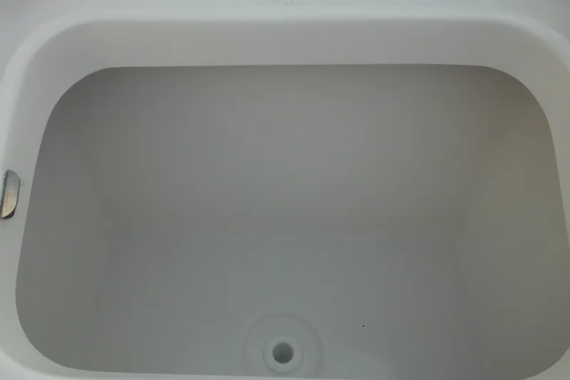 Slide: The Image of 2026 Tidewater 232 LXF boat compartment, white interior, drain hole visible. - 8