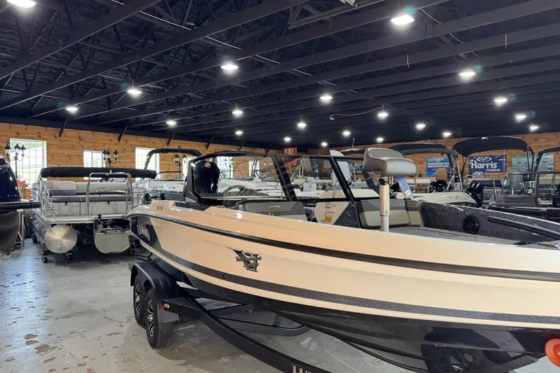 Slide: The Image of 2026 Lund 202 Pro-V GL boat displayed indoors on a trailer. - 1