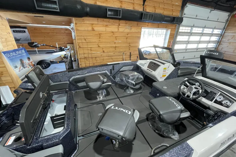 Slide: The Image of 2026 Lund 202 Pro-V GL boat interior with seating and steering wheel in showroom. - 11