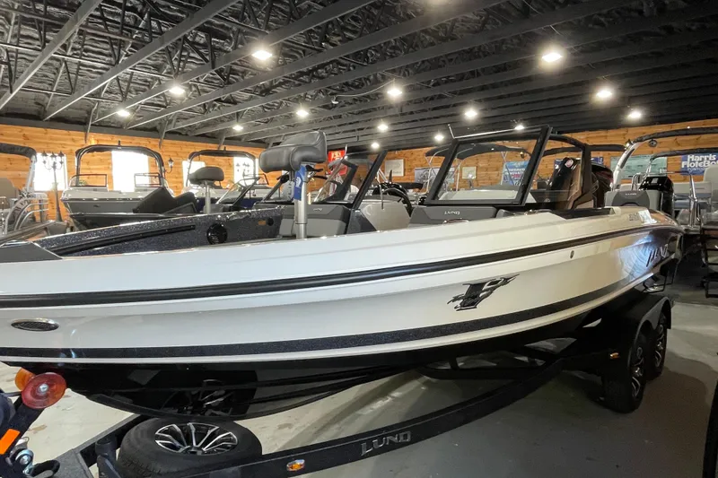 Slide: The Image of 2026 Lund 202 Pro-V GL boat displayed in a showroom with wooden walls. - 12