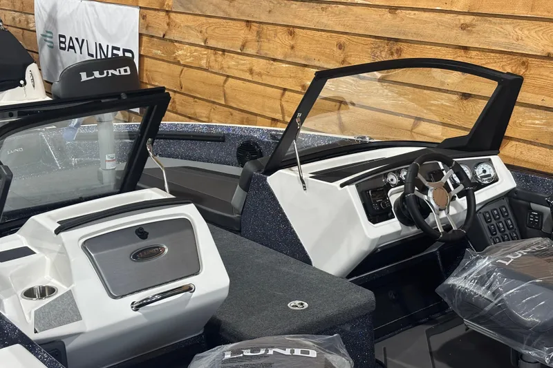 Slide: The Image of 2026 Lund 202 Pro-V GL boat interior with steering wheel and dashboard, displayed indoors. - 4