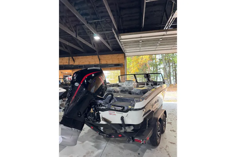 Slide: The Image of 2026 Lund 202 Pro-V GL boat in garage, featuring powerful outboard motor. - 5