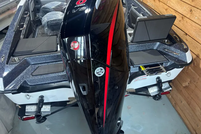 Slide: The Image of 2026 Lund 202 Pro-V GL boat interior with steering wheel and seating in wooden garage. - 8