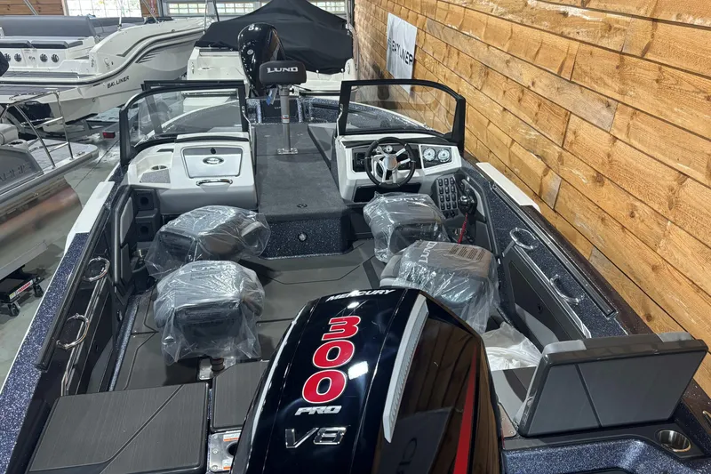 Slide: The Image of 2026 Lund 202 Pro-V GL boat displayed in a showroom with other boats. - 9