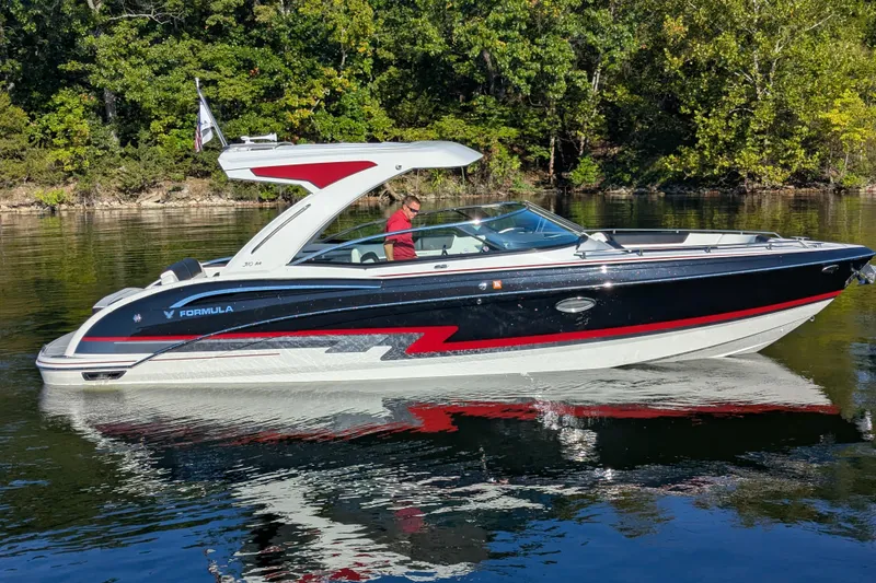 Slide: The Image of 2021 Formula 310 Bowrider I/O boat cruising on a calm lake with lush green trees. - 21