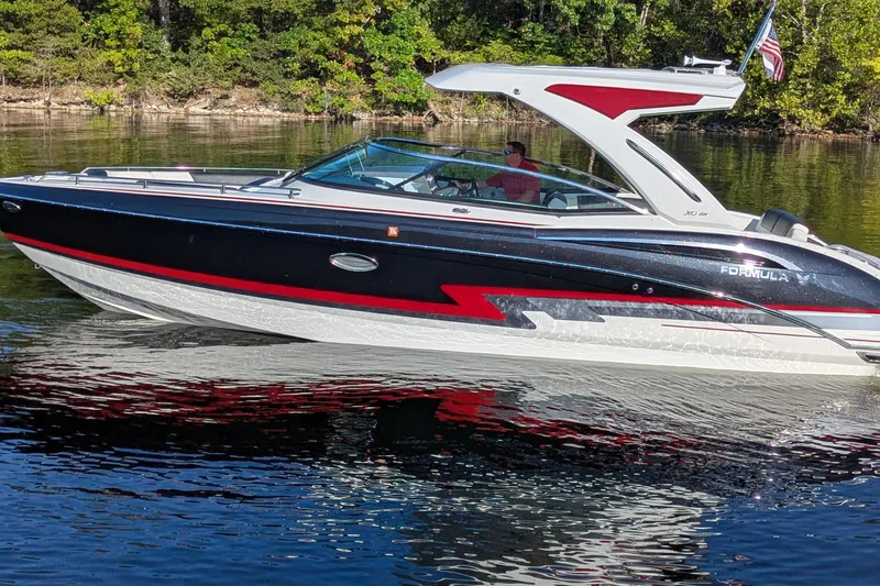 Slide: The Image of 2021 Formula 310 Bowrider I/O boat cruising on a calm lake with lush green shoreline. - 24