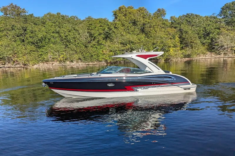 Slide: The Image of 2021 Formula 310 Bowrider I/O boat cruising on a calm lake with forest backdrop. - 27