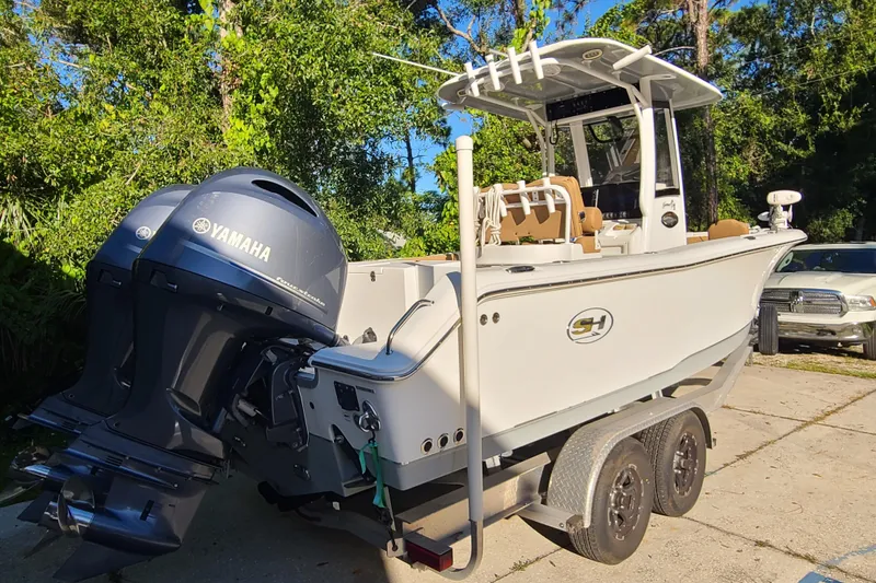 Slide: The Image of 2018 Sea Hunt Gamefish 25 boat with Yamaha engines on a trailer, parked outdoors. - 2