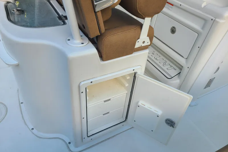 Slide: The Image of 2018 Sea Hunt Gamefish 25 boat interior with open storage compartment and brown seating. - 26