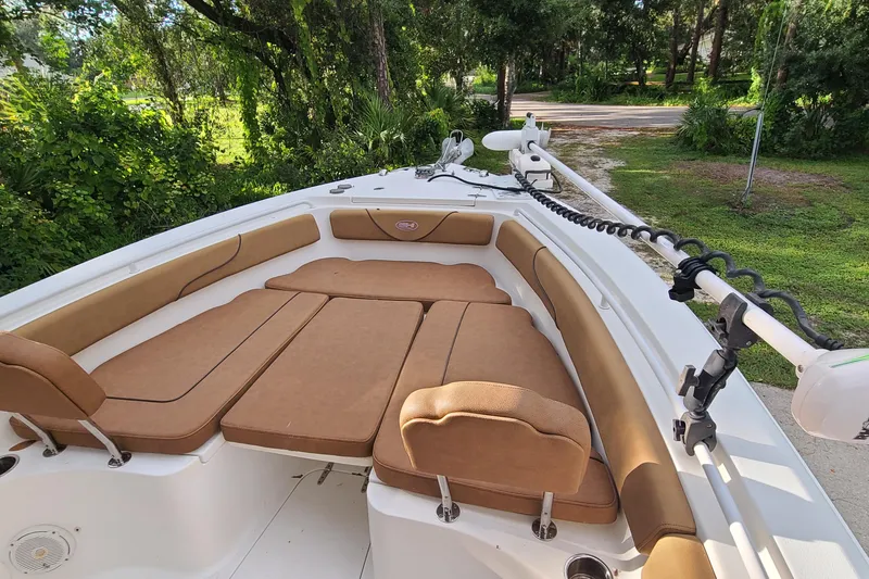Slide: The Image of 2018 Sea Hunt Gamefish 25 boat with cushioned seating and lush greenery background. - 4