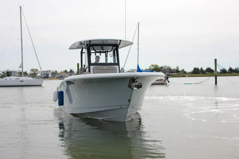 Slide: The Image of 2026 Sea Hunt Gamefish 28 Forward Seating boat on calm water, with sailboats in background. - 2