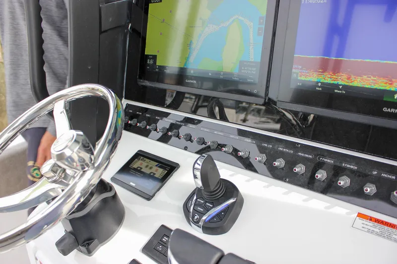 Slide: The Image of 2026 Sea Hunt Gamefish 28 dashboard with steering wheel, navigation screens, and control switches. - 48