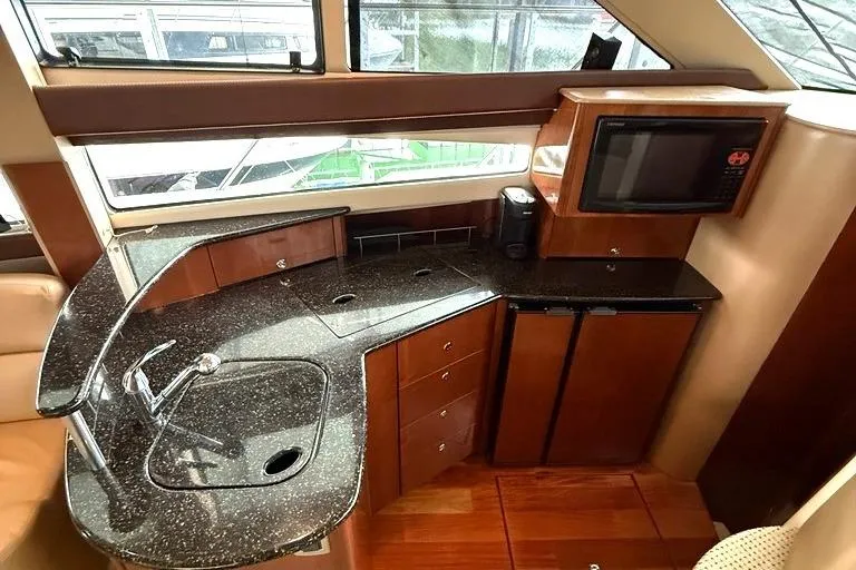 Slide: The Image of 2008 Meridian 391 yacht kitchen with granite countertops, sink, microwave, and wood cabinetry. - 24