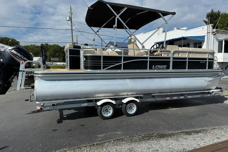 Slide: The Image of 2015 Lowe SS 230 pontoon boat on trailer, featuring a Mercury outboard motor. - 6