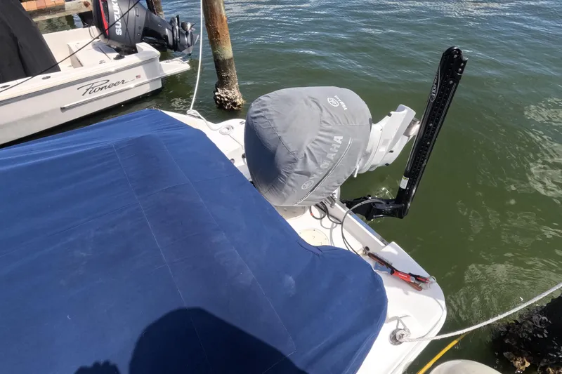 Slide: The Image of 2012 Robalo R247 Dual Console boat with blue cover docked by the water. - 119