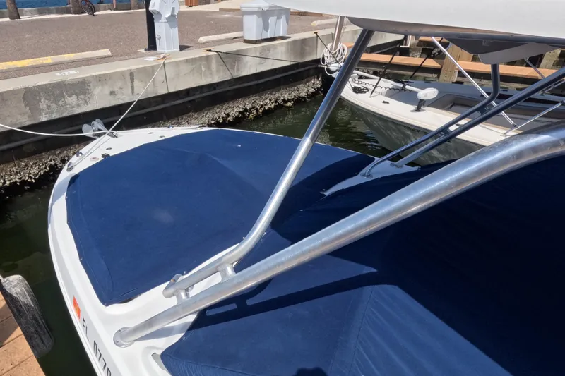 Slide: The Image of 2012 Robalo R247 Dual Console boat with blue cover and metal frame, docked by the water. - 121