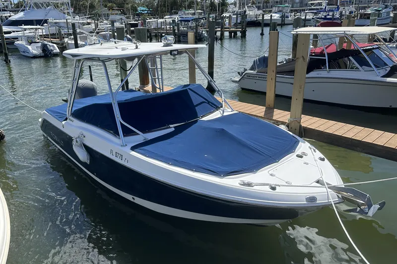 Slide: The Image of 2012 Robalo R247 Dual Console boat docked in marina, covered with blue tarp. - 125