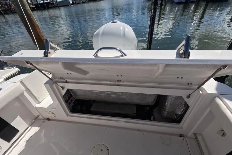 Slide: The Image of 2012 Robalo R247 Dual Console boat with open storage compartment by the water. - 13