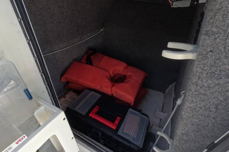 Slide: The Image of Storage compartment in 2012 Robalo R247 Dual Console with life jackets and toolbox. - 24