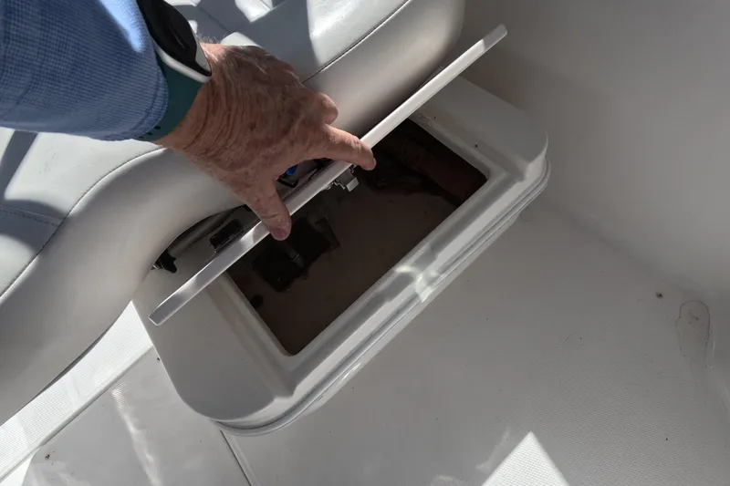 Slide: The Image of 2012 Robalo R247 Dual Console storage compartment being opened on a boat. - 41