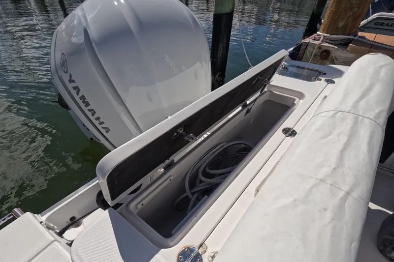Slide: The Image of 2012 Robalo R247 Dual Console with Yamaha engine, open storage compartment, docked on water. - 43