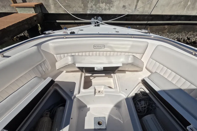 Slide: The Image of 2012 Robalo R247 Dual Console boat interior with white seating and storage compartments. - 53