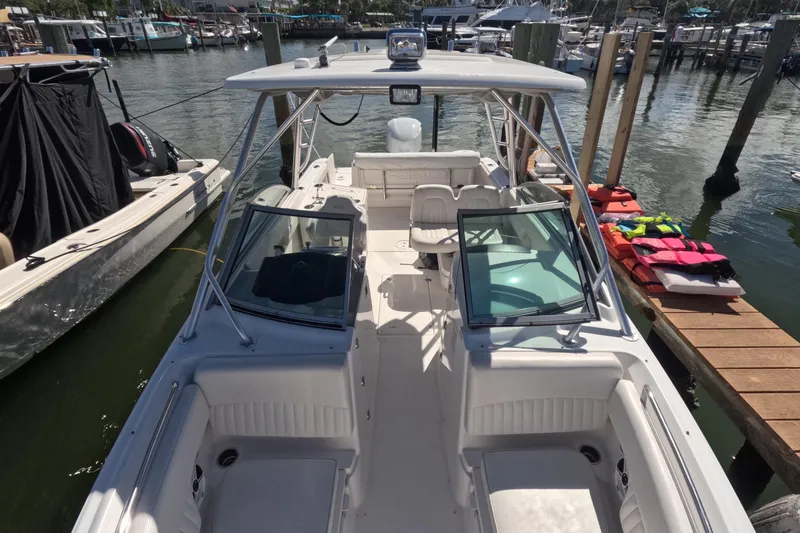 Slide: The Image of 2012 Robalo R247 Dual Console boat docked at marina, featuring spacious seating and clear windshield. - 59