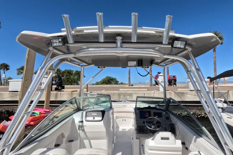Slide: The Image of 2012 Robalo R247 Dual Console boat with T-top and helm, docked under clear blue sky. - 64