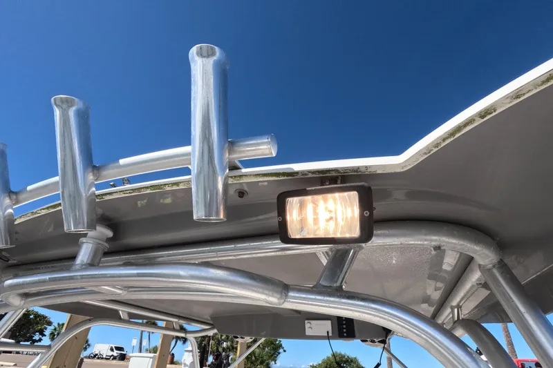Slide: The Image of 2012 Robalo R247 Dual Console boat with rod holders and light under clear blue sky. - 84