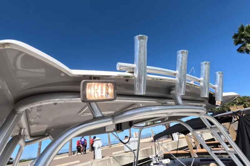 Slide: The Image of 2012 Robalo R247 Dual Console boat with rod holders and light, under clear blue sky. - 85