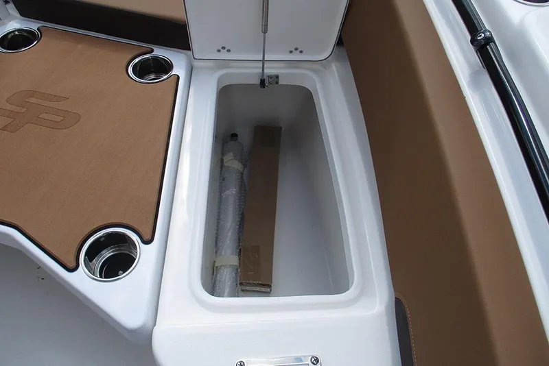 Slide: The Image of 2026 Sea Pro 225FLX Sandbar boat storage compartment with cup holders and brown accents. - 12