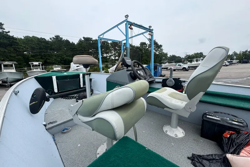 Slide: The Image of 2005 Lund 1675 Adventure SS boat interior with seats and steering wheel in a marina setting. - 7