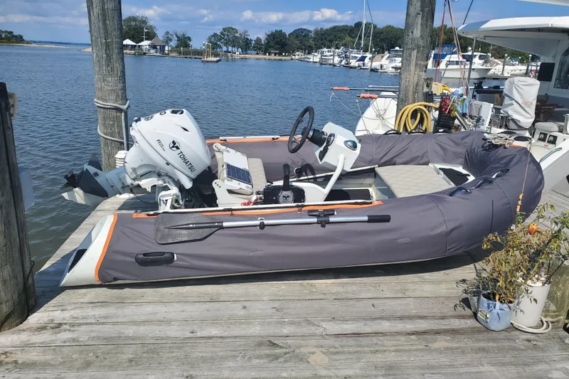 Slide: The Image of Inflatable boat with Tohatsu motor docked, Excess 12 model, 2020, at a marina. - 15
