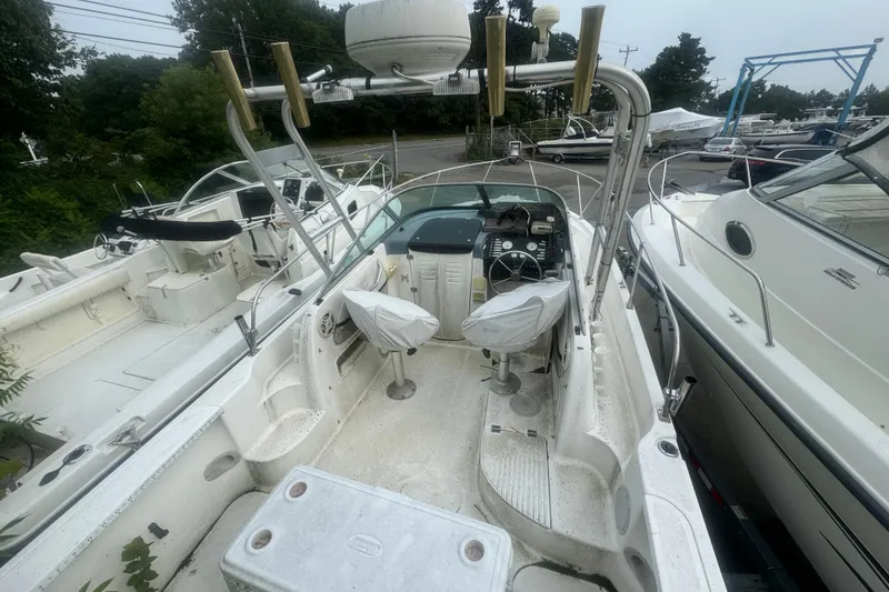 Slide: The Image of 1999 Bayliner 2102 Trophy boat interior with covered seats and control panel, docked outdoors. - 2