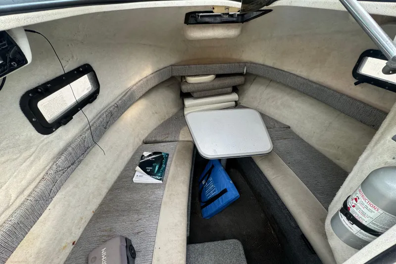 Slide: The Image of 1999 Bayliner 2102 Trophy cabin interior with seating, table, and safety equipment. - 6