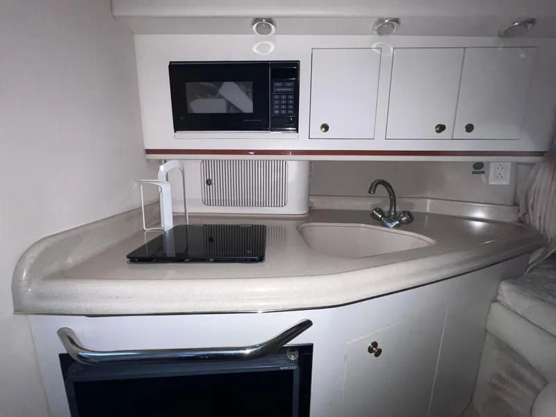 Slide: The Image of Compact kitchen area in a 2000 Sea Ray 290 Amberjack boat with microwave and sink. - 17