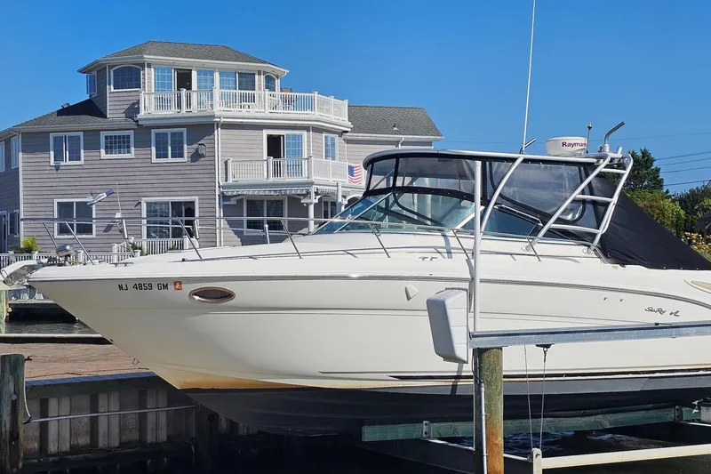 Slide: The Image of 2000 Sea Ray 290 Amberjack boat docked near a waterfront house. - 3