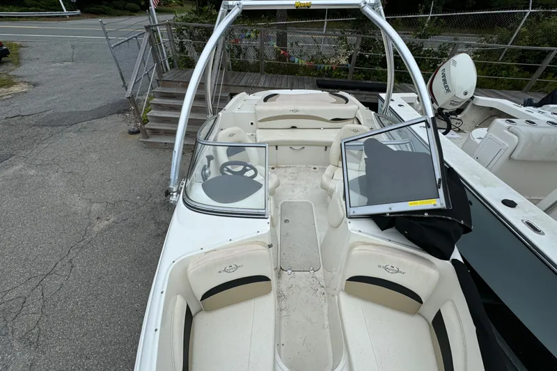 Slide: The Image of 2016 Stingray 198 RX boat with open seating and steering wheel, parked on pavement. - 11